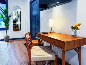 A compact room with a wooden desk, a chair, a lamp, and a potted plant.