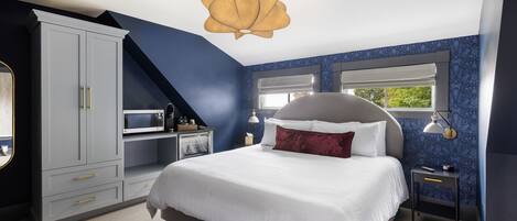 A bedroom with a bed, a wardrobe, a desk, and a window.