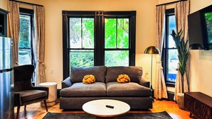 Ein modernes Wohnzimmer mit einem grauen Sofa, einem runden Couchtisch und einem an der Wand befestigten Fernseher.