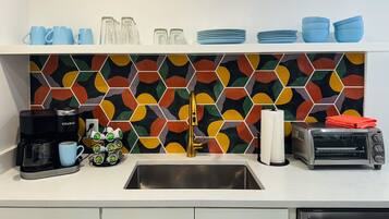 A kitchen with a colorful hexagonal backsplash, a coffee maker, a toaster, and various kitchen items.