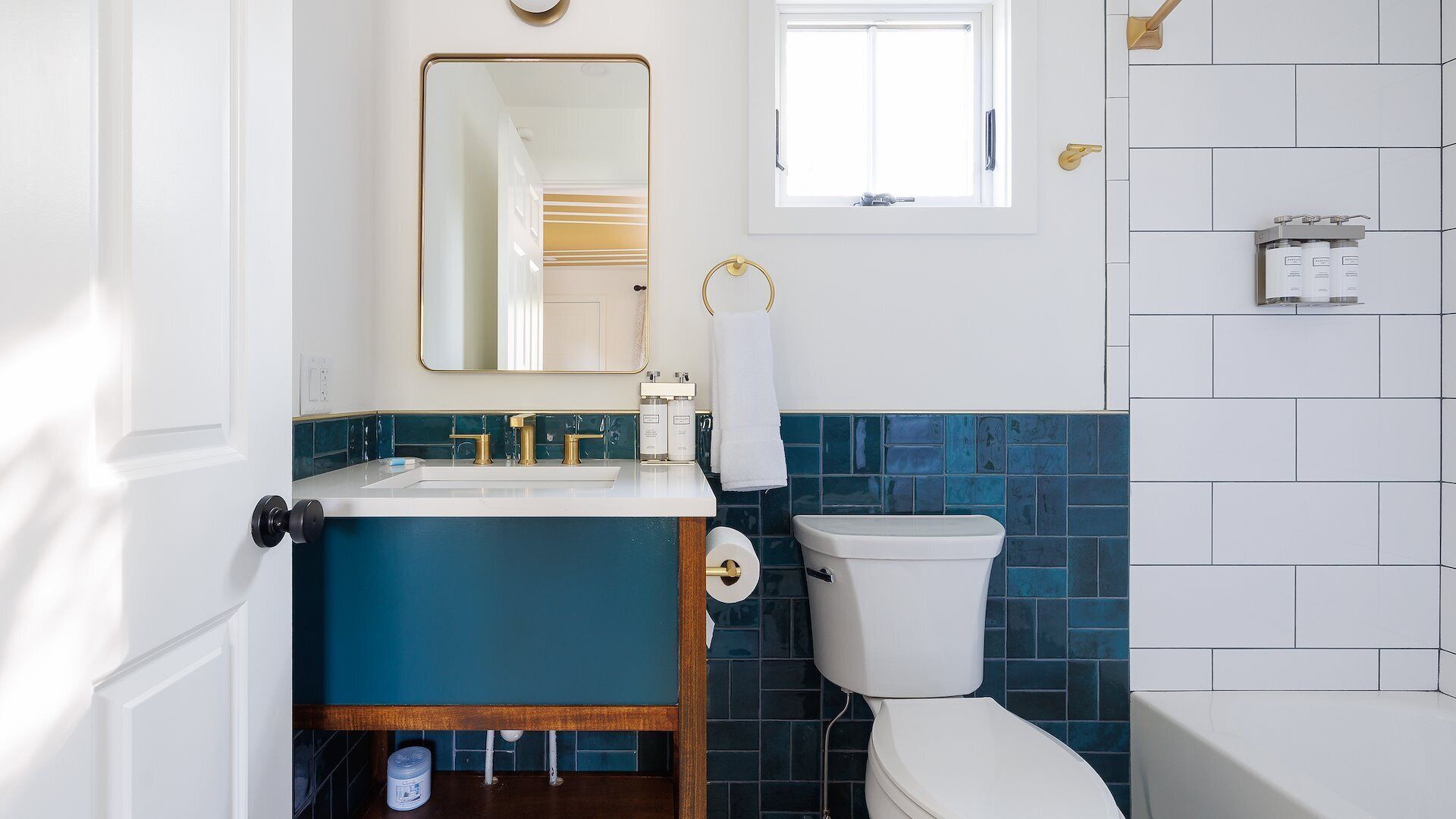 A bathroom with a white toilet, a sink with gold fixtures, and a mirror above it.