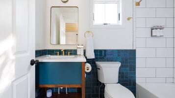 A bathroom with a white toilet, a sink with gold fixtures, and a mirror above it.