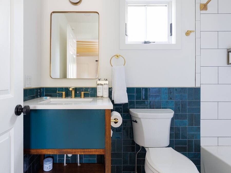 A bathroom with a white toilet, a sink with gold fixtures, and a mirror above it.