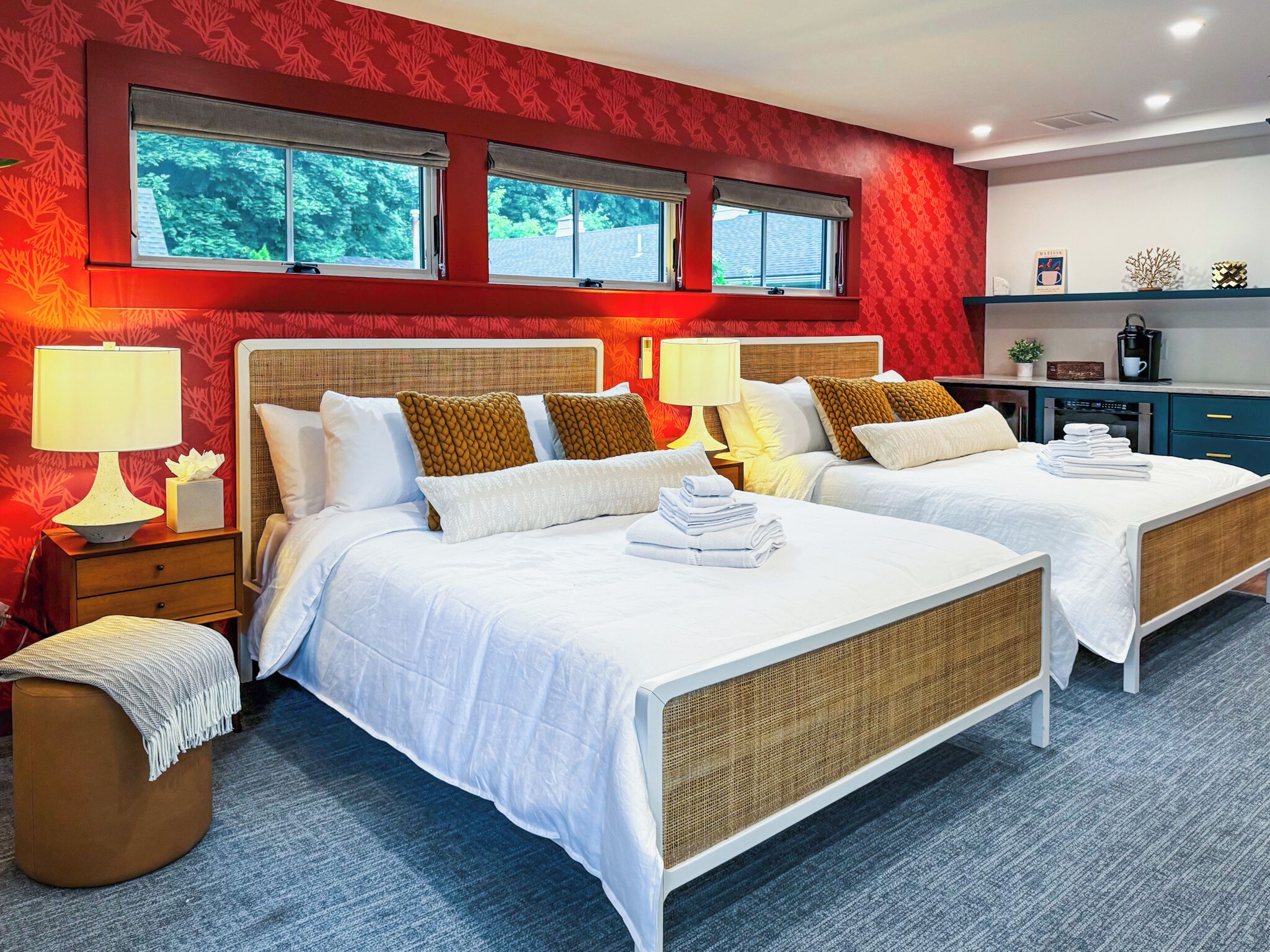 Une chambre d’hôtel avec deux lits, une petite kitchenette et une fenêtre donnant sur des arbres.