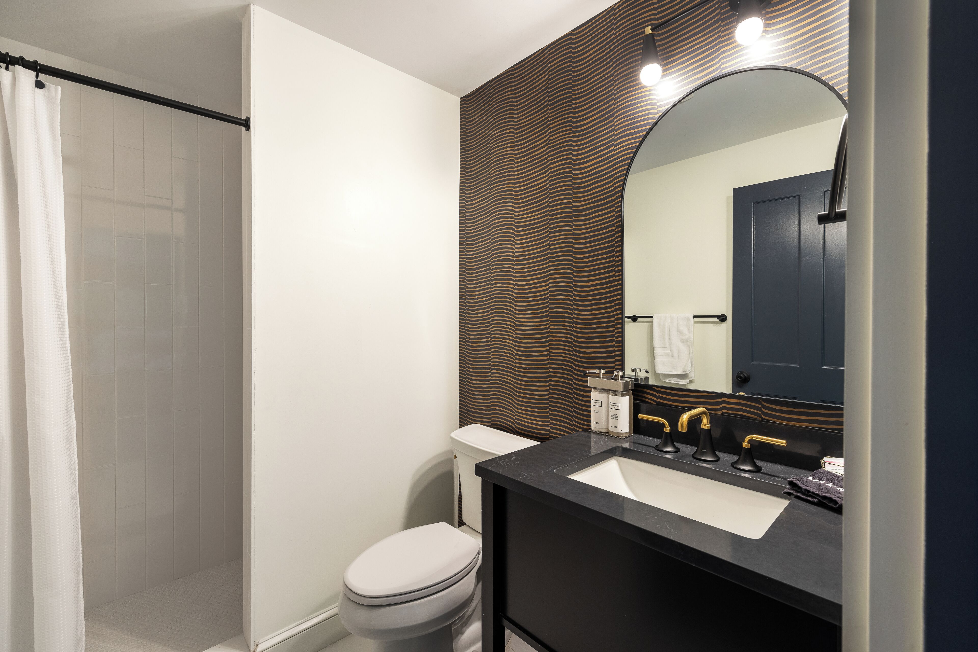A modern bathroom with a shower, toilet, and sink.