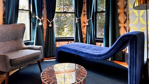 Ein Zimmer mit einem blauen Sofa, einem runden Glastisch und einem Sessel.