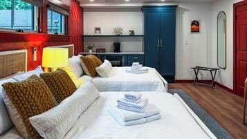 Habitación de hotel con dos camas, un escritorio, un armario y un espejo.