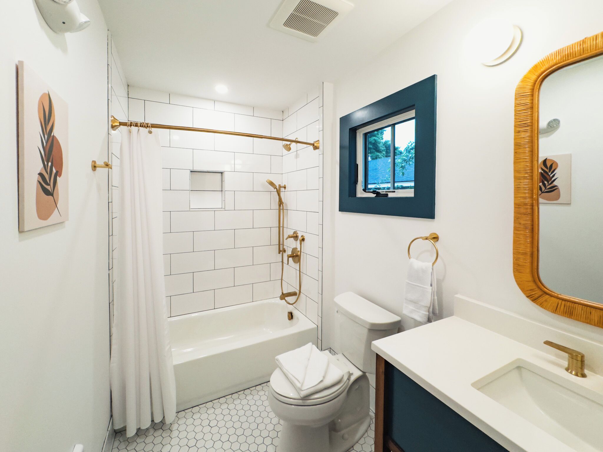 Ein Badezimmer mit einer weißen Badewanne, einer Toilette, einem Waschbecken und einer Dusche mit einer goldfarbenen Duschbrause.