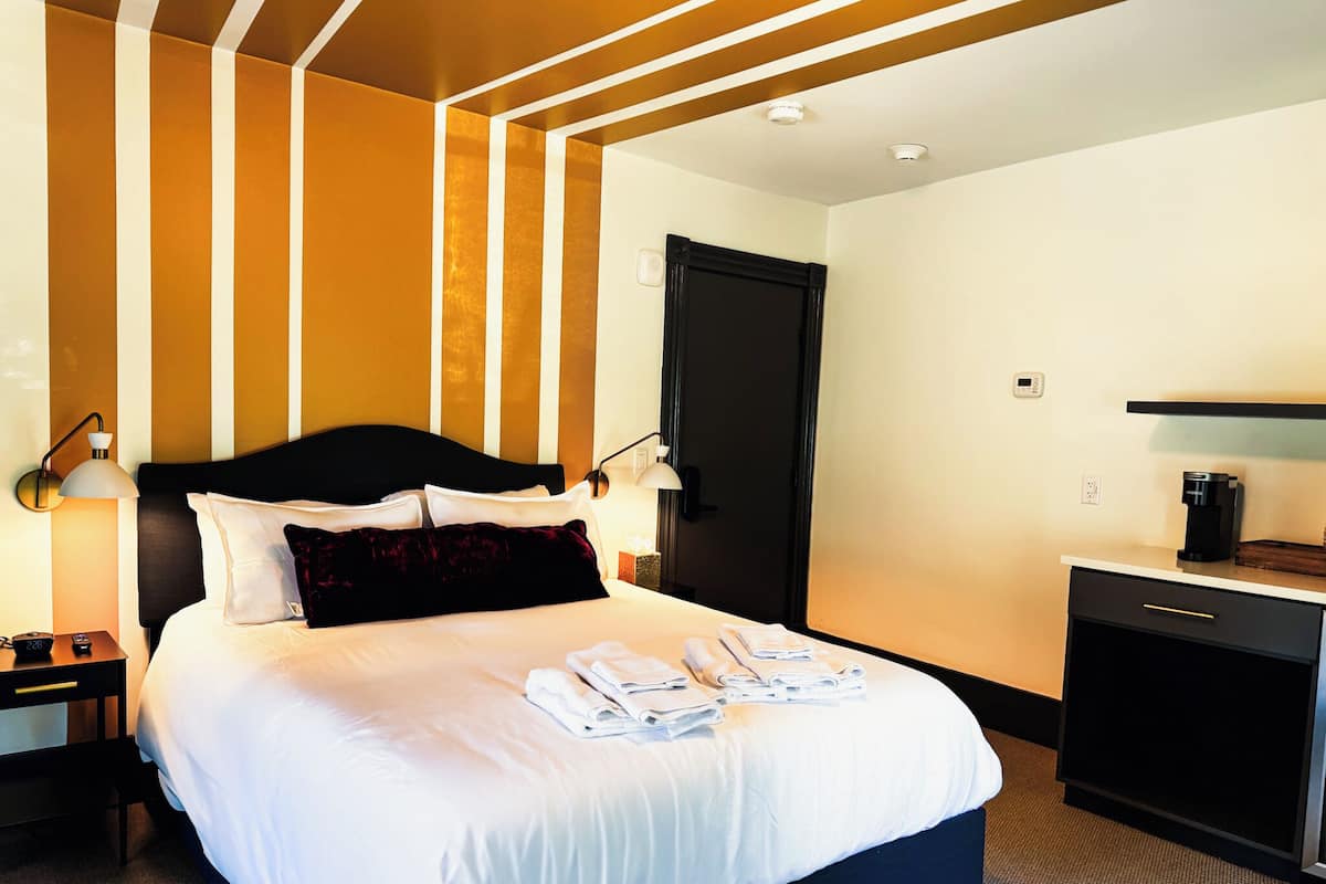 Une chambre d’hôtel avec un grand lit, des tables de chevet, un bureau et une armoire.