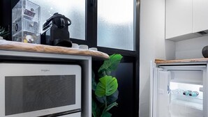 Una cocina con microondas, un refrigerador pequeño y una planta.