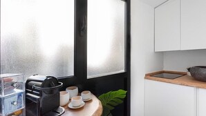 Una cocina compacta con cafetera, tazas y una planta.