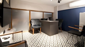 A modern conference room with a large screen, a podium, and two upholstered chairs. - Demhat Hotel Old City (Istanbul)