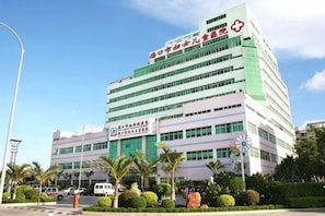 A multi-story building with a prominent red and white sign indicating a medical facility. - Courtyard by Marriott (Hainan College of Commerce and Industry Provincial Museum Store) (Haikou)