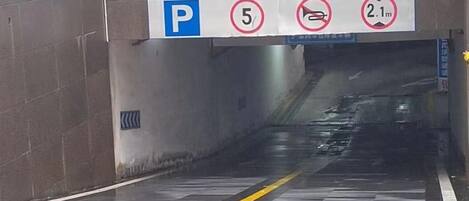 Señal de estacionamiento con símbolo de 'P', símbolo de prohibido estacionar y restricción de altura de 2.1 metros.