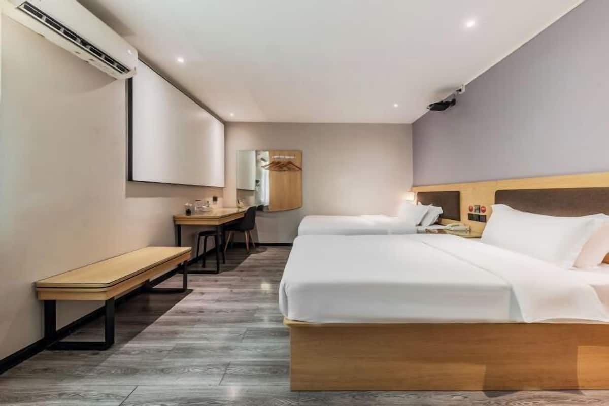 A hotel room with two beds, a desk, a chair, and a wardrobe.
