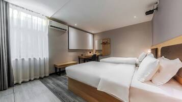 A hotel room with a bed, bedside table, desk, chair, and a large mirror.