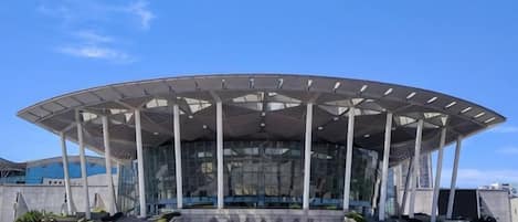A modern building with a large, open, covered central area and a staircase leading up to it.