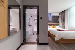 A modern hotel room with a large bed, a bathroom with a toilet and sink, and a view of the city through the window. - Courtyard by Marriott (Hainan College of Commerce and Industry Provincial Museum Store) (Haikou)