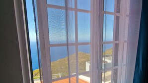 A room with a large window offering a view of a coastal landscape.