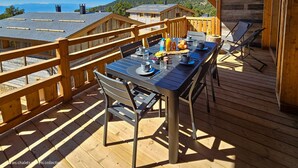 A wooden deck with a table set for two, overlooking a mountainous landscape. - Appartement B-12 T2 Cabine (Font-Romeu-Odeillo-Via)