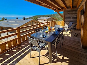 A wooden deck with a table set for two, overlooking a mountainous landscape. - Appartement B-12 T2 Cabine (Font-Romeu-Odeillo-Via)