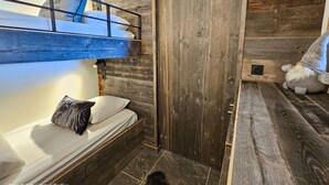 A bunk bed with a wooden headboard, a door, and a small gnome figure. - Appartement B-12 T2 Cabine (Font-Romeu-Odeillo-Via)
