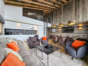 A modern living room with a sofa set, a coffee table, and a dining area with chairs and a table.