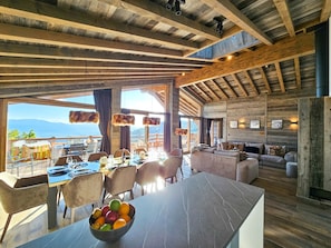 Un cuarto amplio con una gran mesa de comedor, asientos cómodos y vistas a las montañas.