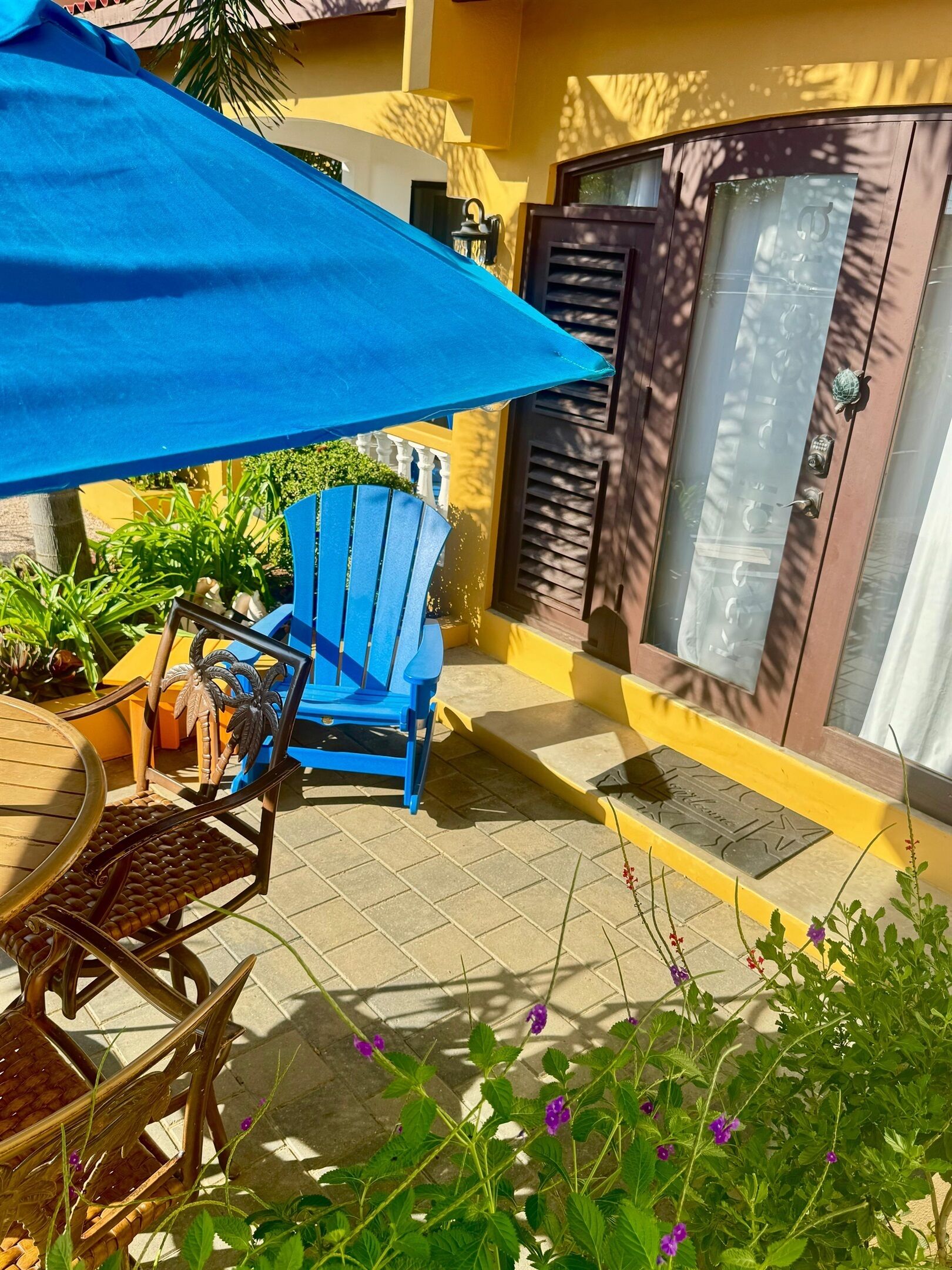Eine Terrasse mit blauem Stuhl, einem Tisch und einem Blumentopf.