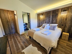 Une chambre à coucher moderne avec un grand lit, des murs en bois et une petite table de chevet.