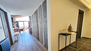 Ein Flur mit Holzboden, einem schwarzen Metalltisch und Dekorationselementen, mit Blick in einen Essbereich.