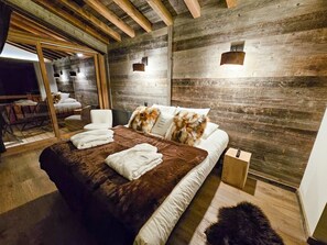 A bedroom with a large bed, a wooden ceiling, and a mirror.
