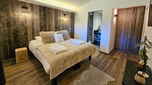 Ein modernes Schlafzimmer mit einer Wand in Holzoptik, einem Bett mit weißer Bettwäsche und einem kleinen Nachttisch.