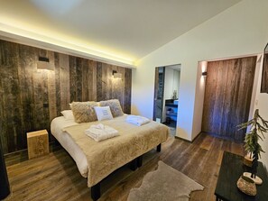 A modern bedroom with a wooden accent wall, a bed with white linens, and a small bedside table.