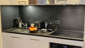 A modern kitchen with a microwave, toaster, kettle, and induction cooktop. - Appartement B-13 T2 Cabine (Font-Romeu-Odeillo-Via)