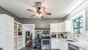 A modern kitchen with white cabinets, stainless steel appliances, and a wooden floor. - Riverbend Hideaway - 5 Min to Downtown & Tubing (San Marcos)