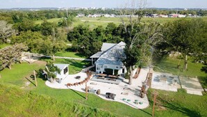 A large house with a spacious patio, surrounded by a lush green landscape. - Riverbend Hideaway - 5 Min to Downtown & Tubing (San Marcos)
