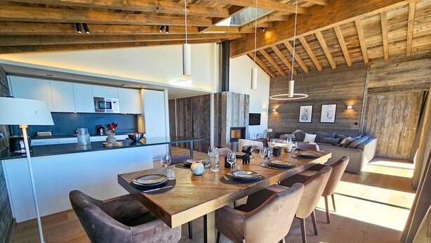 Une cuisine moderne dotée d’un îlot central, de planchers en bois et d’un coin repas avec une longue table et des chaises.