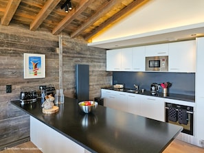 Una cocina moderna con una isla grande, armarios blancos, un microondas y un lavavajillas.