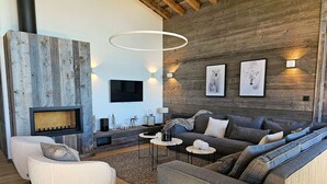 Un salon moderne avec une cheminée, un grand ensemble de canapés et un mur d’accent en bois.