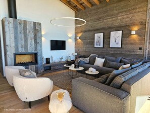 A modern living room with a fireplace, a large sofa set, and a wooden accent wall.
