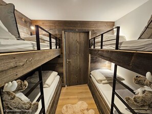A bunk bed room with wooden walls and a door.