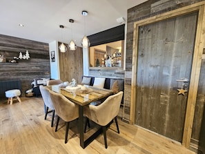 A dining area with a wooden table, chairs, and pendant lighting. - Appartement T2-Cabine A-02 - Collection Cassiopée (Font-Romeu-Odeillo-Via)