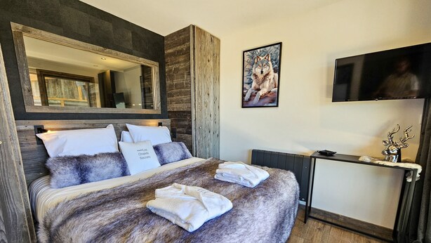 Un dormitorio con una cama grande, un espejo, un televisor y una decoración con cabeza de ciervo.