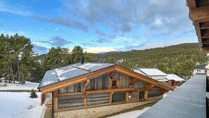 Una cabaña de madera con cimientos de piedra, ventanas grandes y techo inclinado.