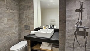 A modern bathroom with a white sink, a toilet, and a shower.