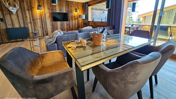 A modern living room with a wooden wall, a glass dining table, and comfortable seating.