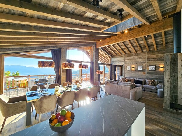A spacious room with a large dining table, comfortable seating, and a view of the mountains.