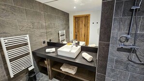 A modern bathroom with a large mirror, a white sink, and a shower area.