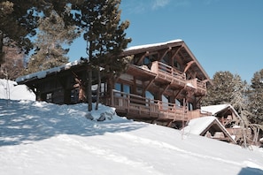 Una cabaña de madera con balcón, rodeada de árboles cubiertos de nieve.